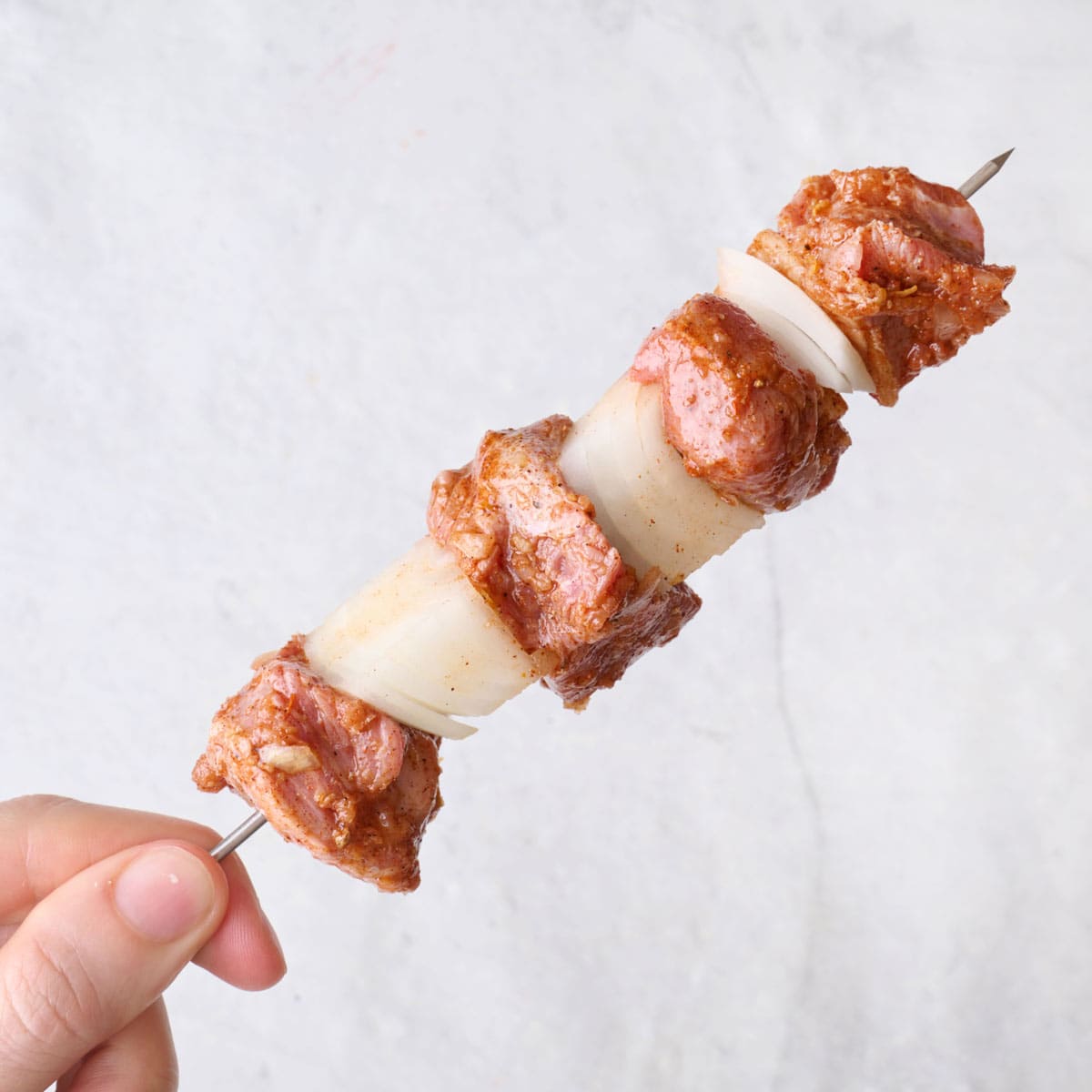 Lamb cubes threaded on a skewer, alternating with onion chunks.