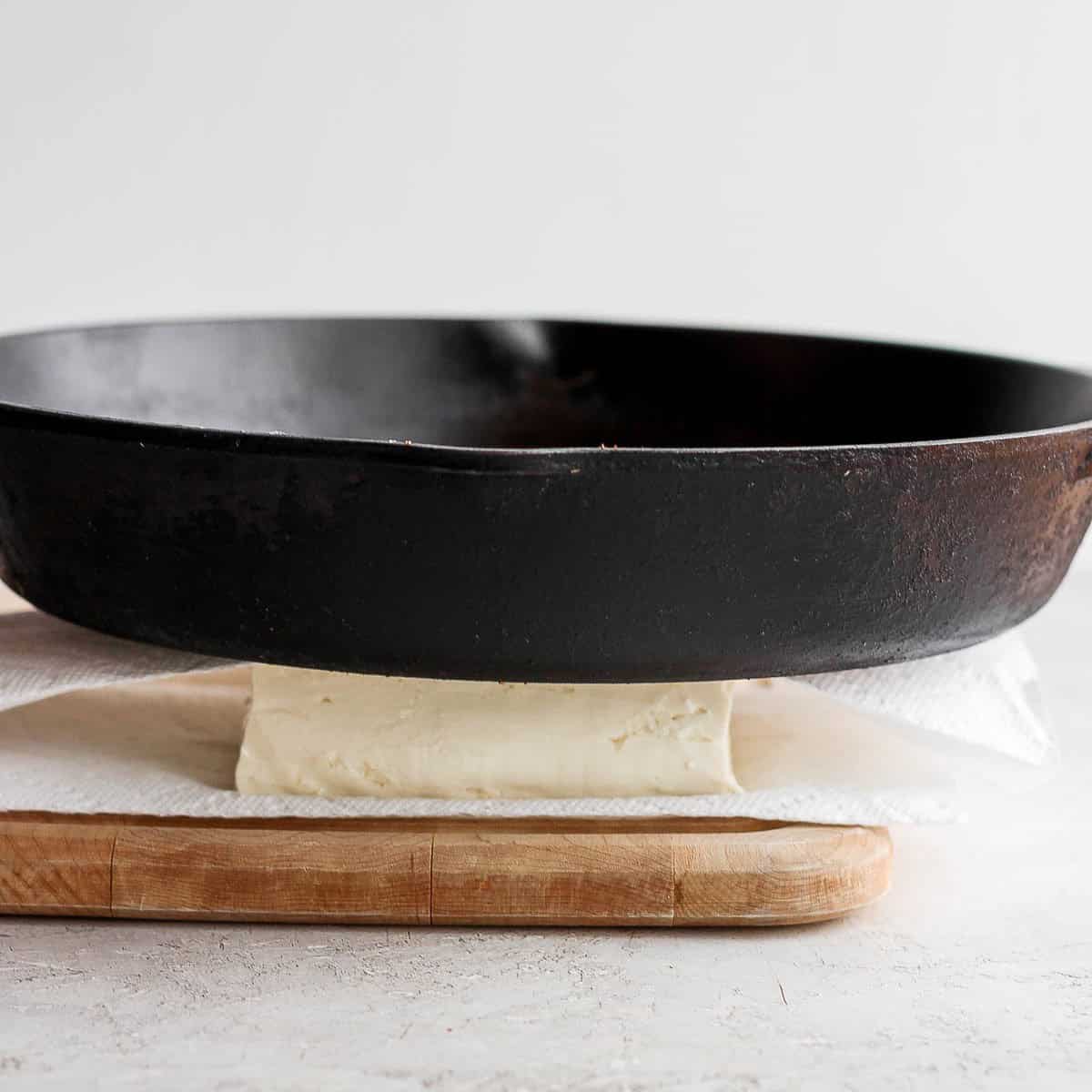 Cast iron skillet pressing tofu.