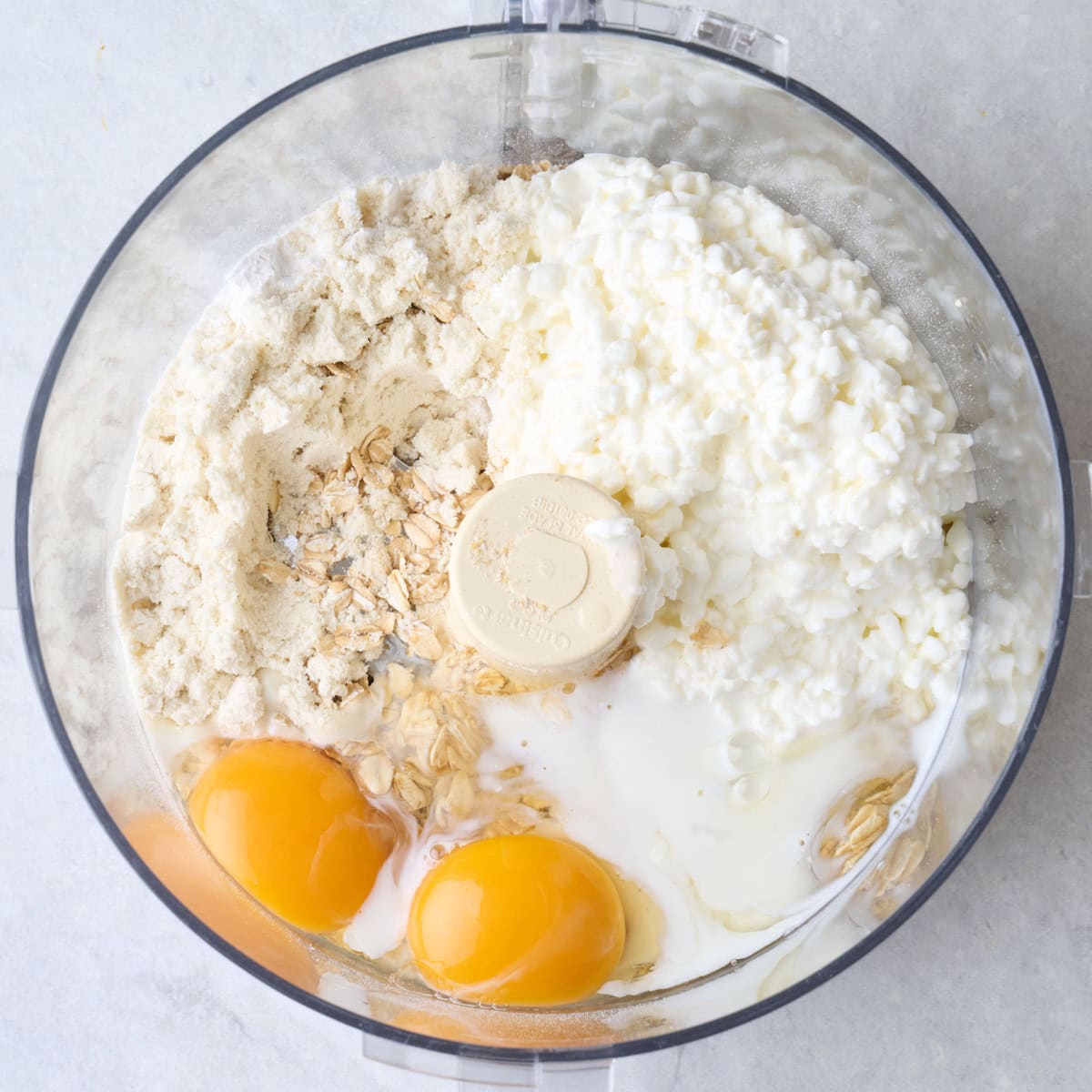 Waffle batter ingredients in the bowl of a food processor before processing.