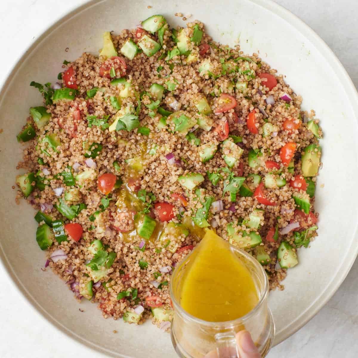 Pouring dressing over salad in a bowl.