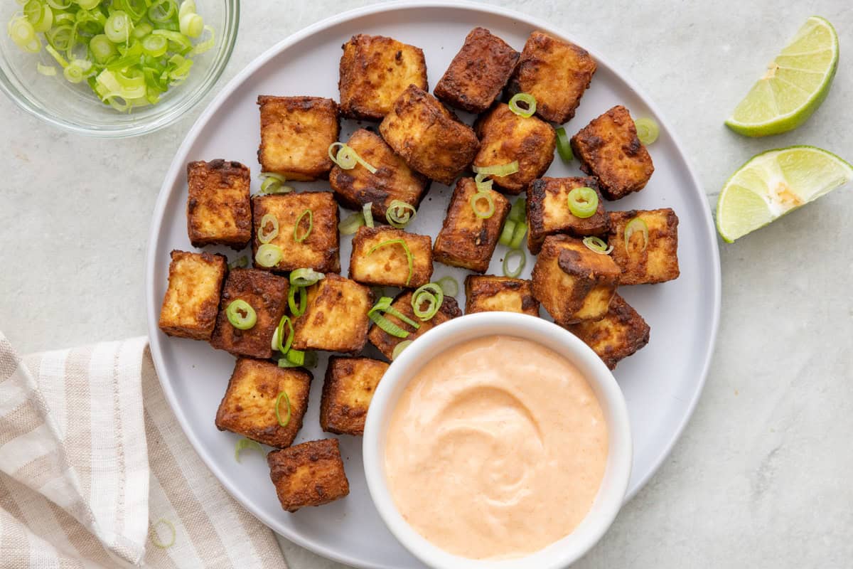Air fryer tofu cubes on a plate with sauce.