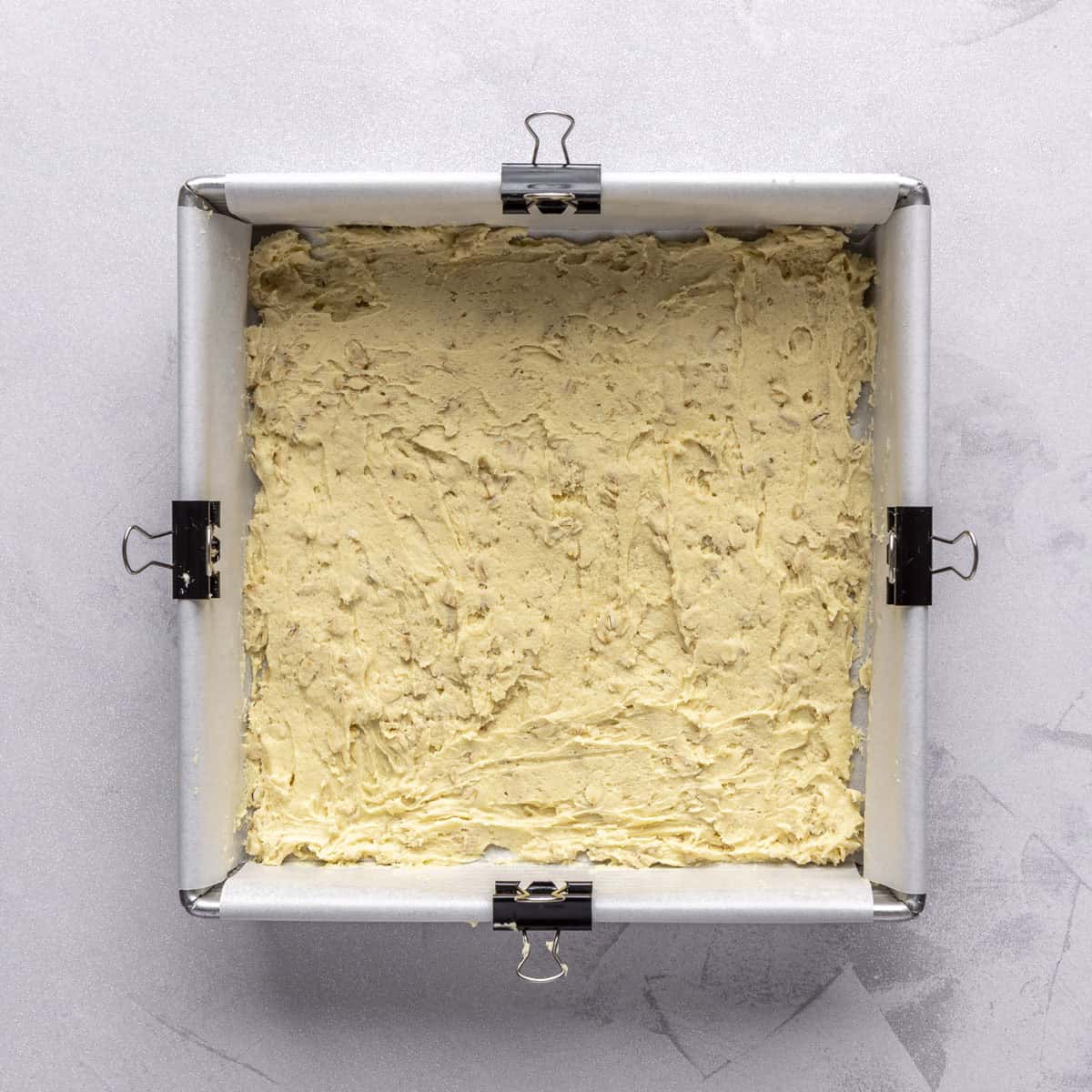 Dough spread into a parchment lined square baking dish.