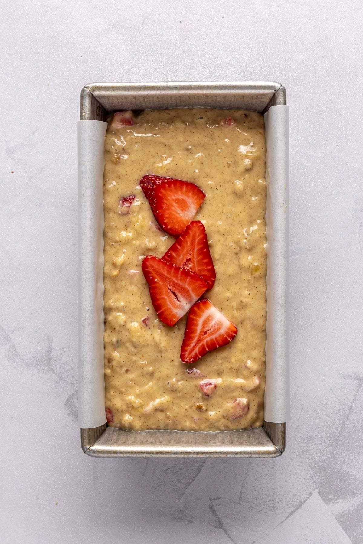 Bread batter in parchment lined loaf pan.