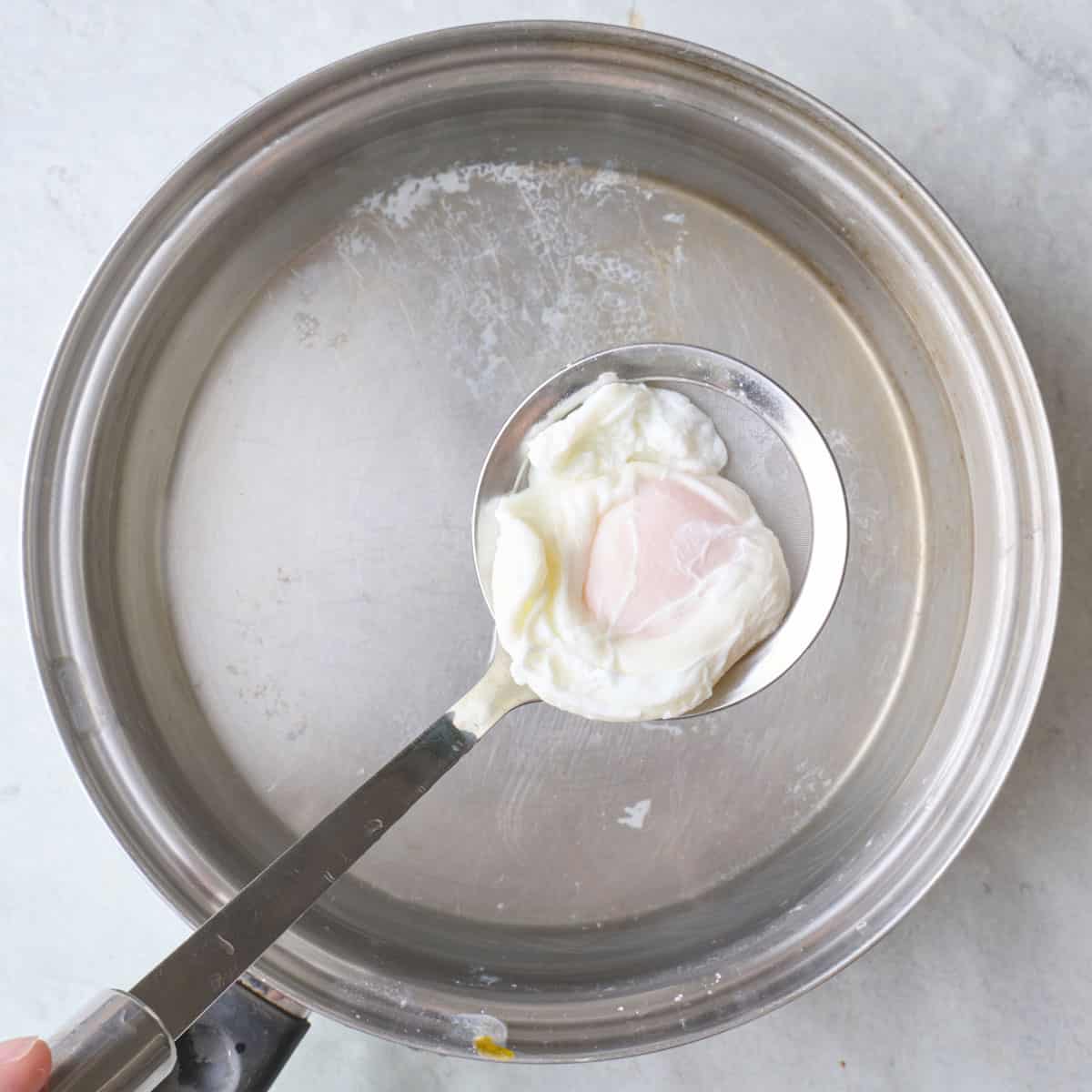 Lifting a poached egg out of water after cooking.
