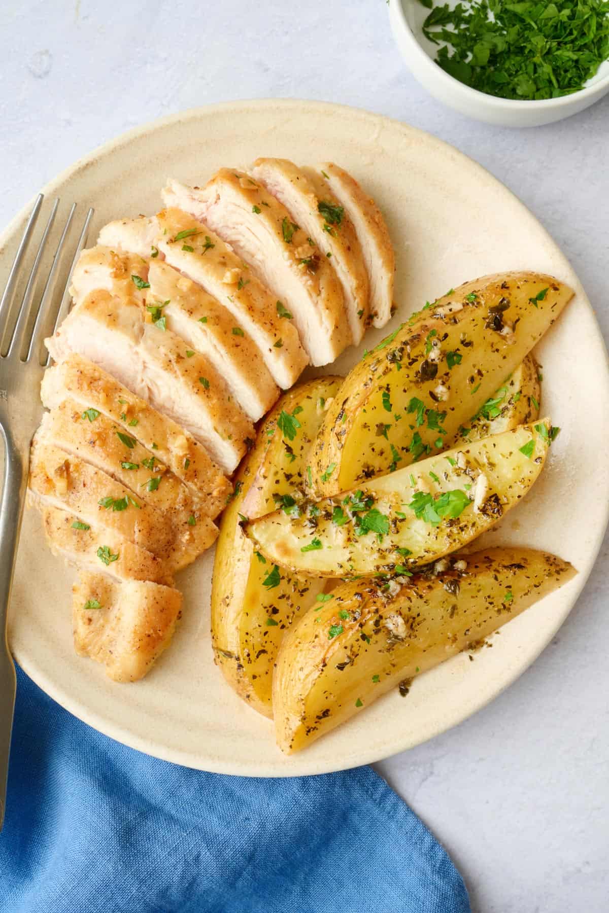 Serving of roasted greek lemon potatoes on a plate with sliced chicken.