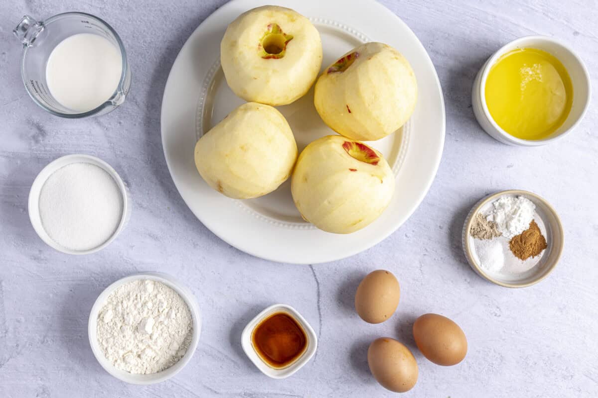 Ingredients for recipe: peeled whole apples, milk, sugar, flour, vanilla, eggs, spices, and melted butter.