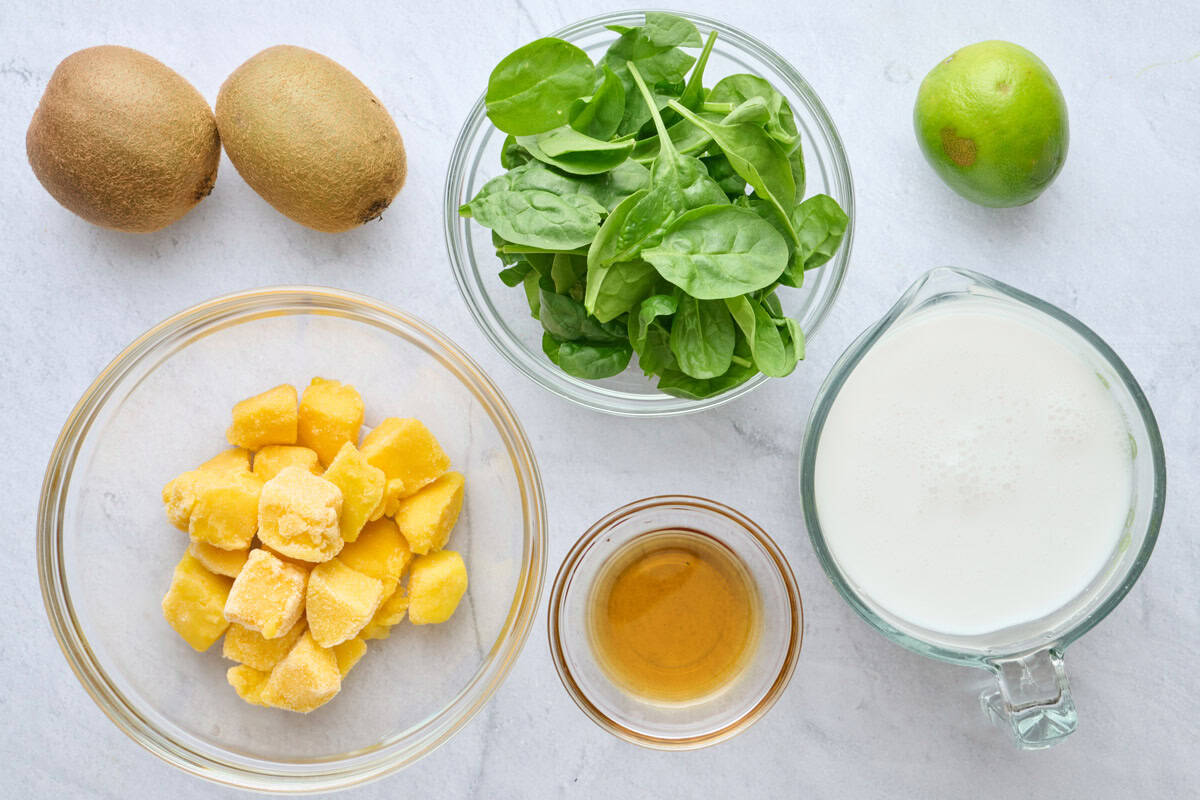 Ingredients for recipe: fresh kiwi, frozen mango chunks, fresh spinach, maple syrup, coconut milk, and lime.