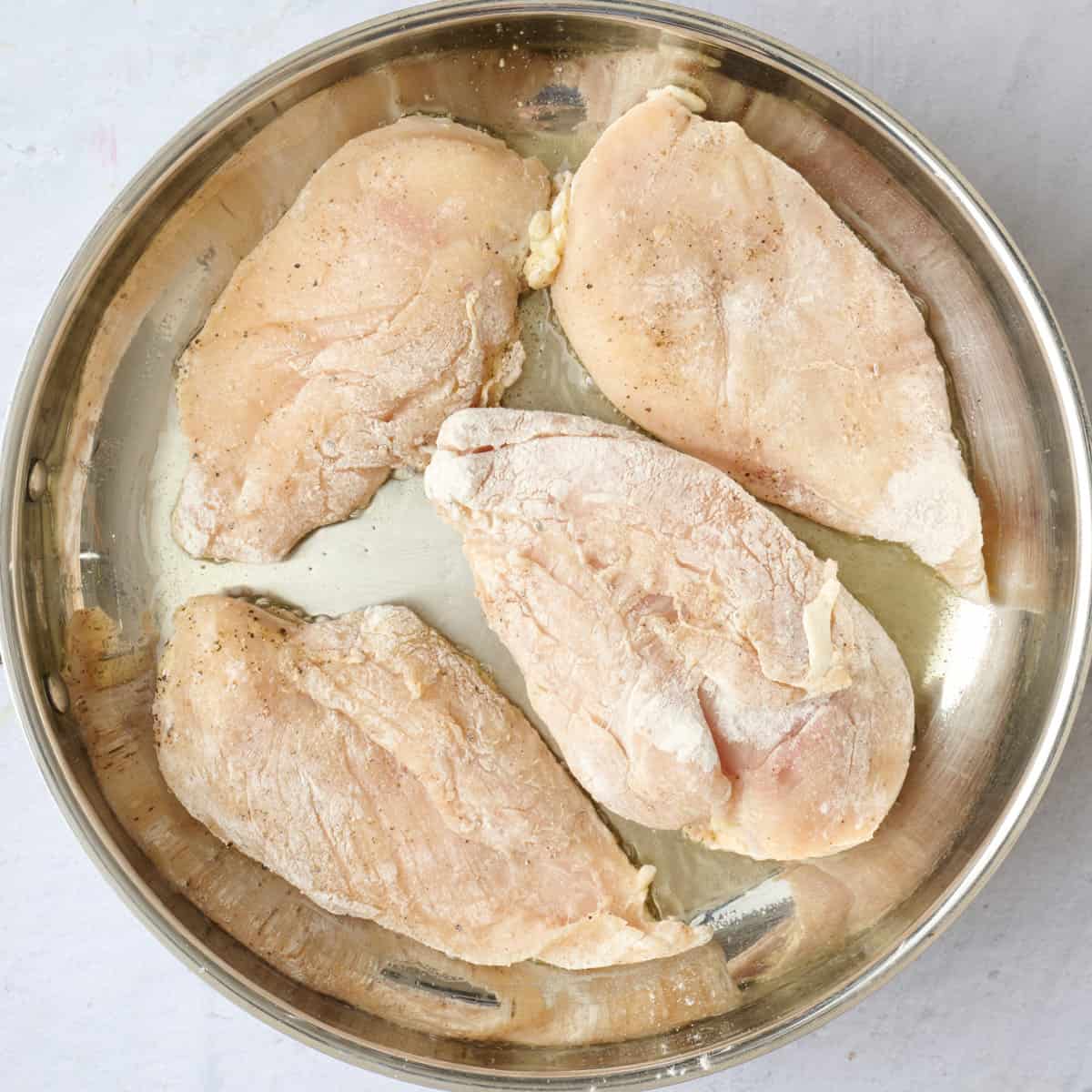 Dredged chicken cutlets in an oiled skillet.