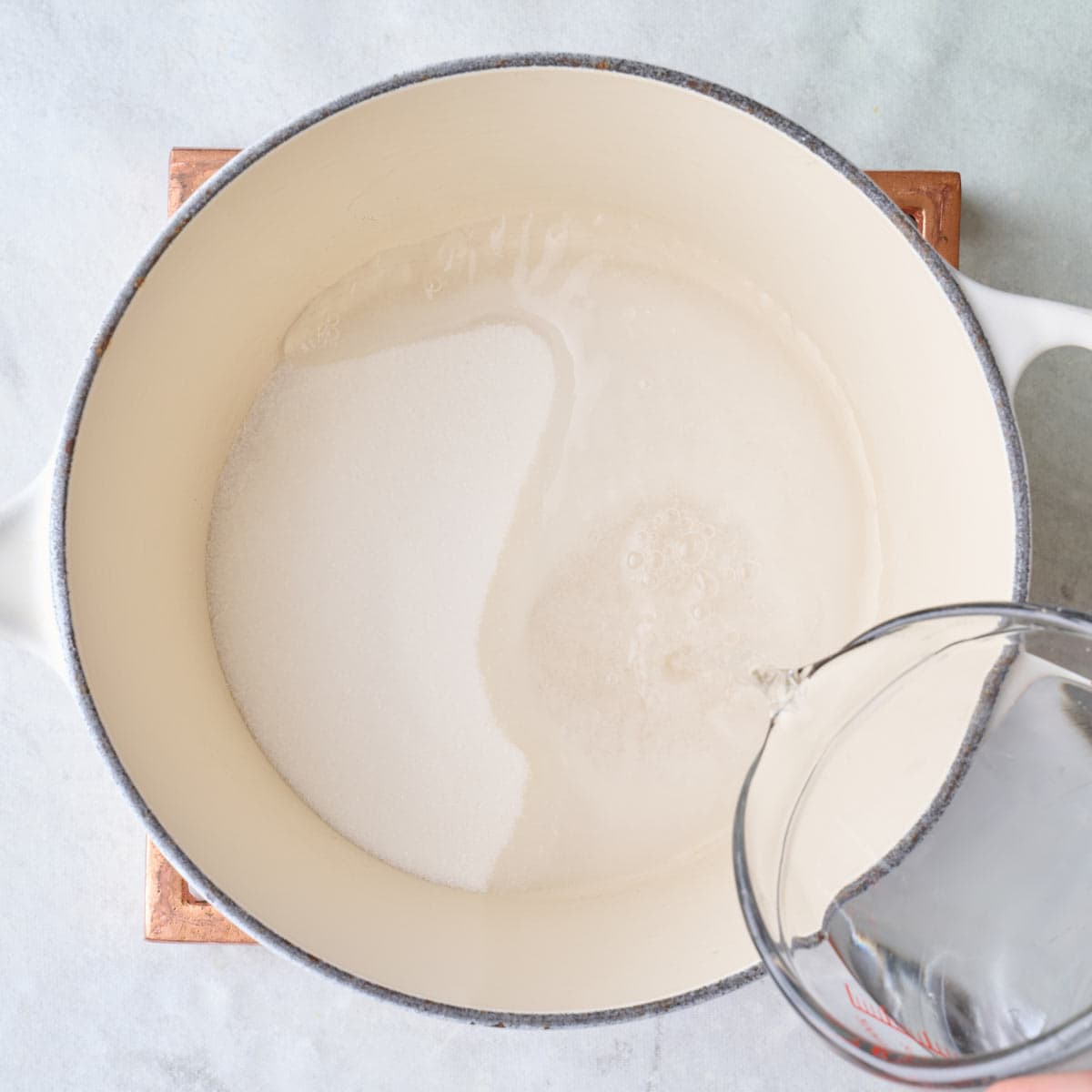 Water being poured into a pot with sugar.