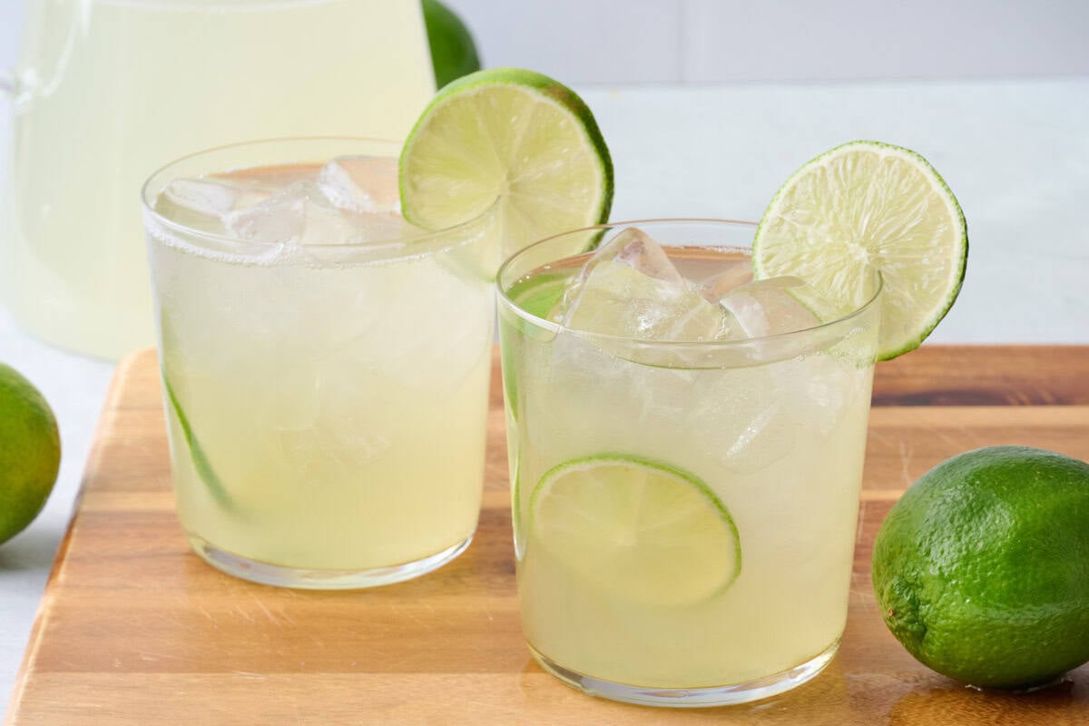 Two glasses of homemade limeade with lime slices tucked into glass and on rim.