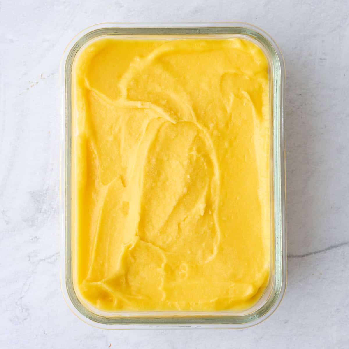 Frozen mango sorbet in a glass dish.