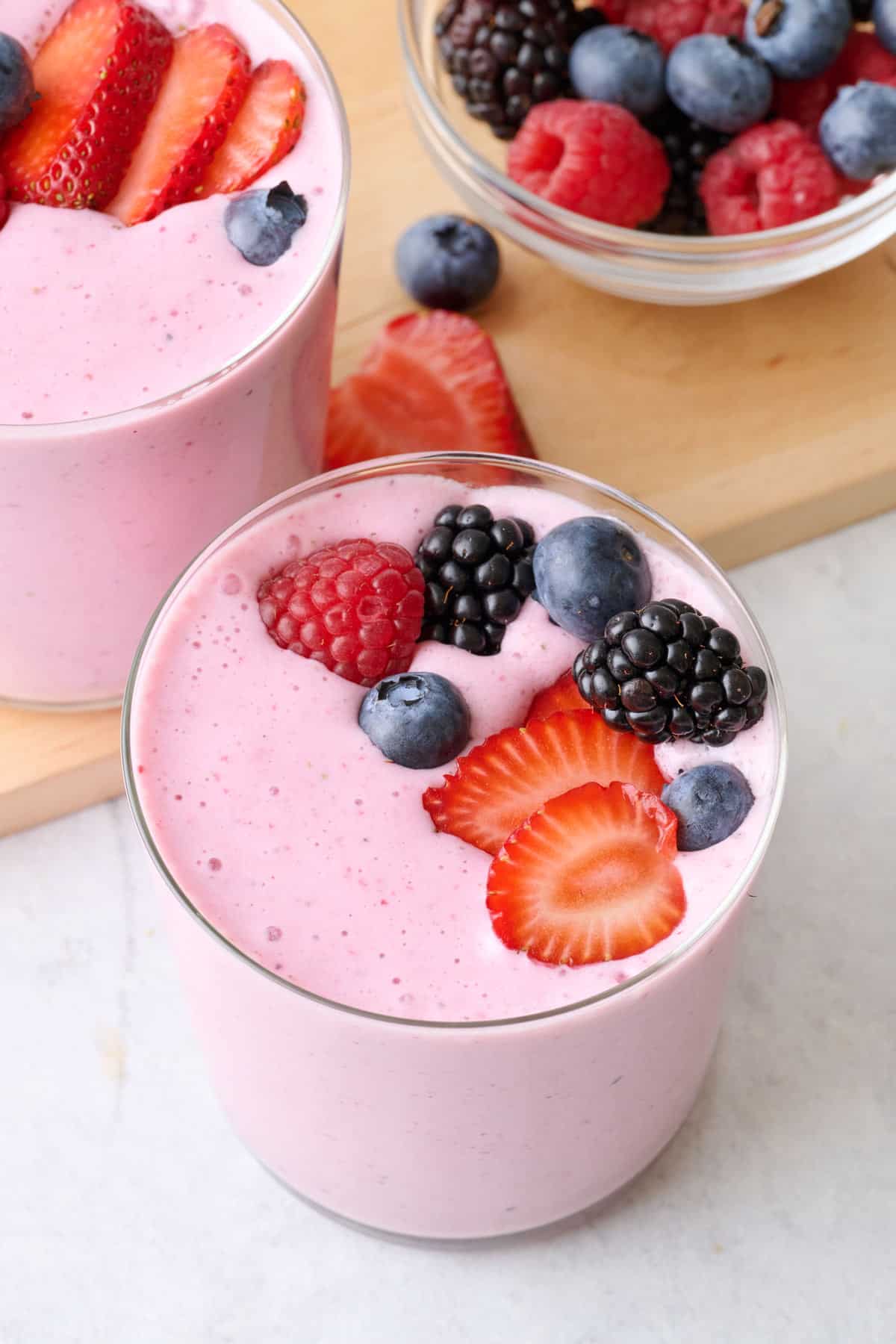 Mixed Berry smoothie glass topped with fresh strawberries, raspberries, blueberries and blackberries.