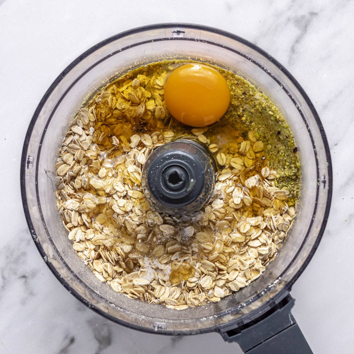 Pistachio and almond flour in a food processor after processing with oats, butter, honey, egg and salt added.