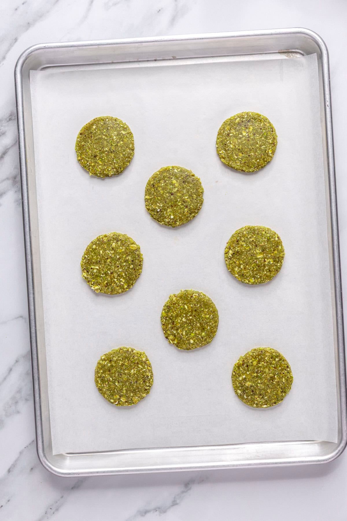 Cookies scooped and flattened on a parchment lined baking sheet before baking.