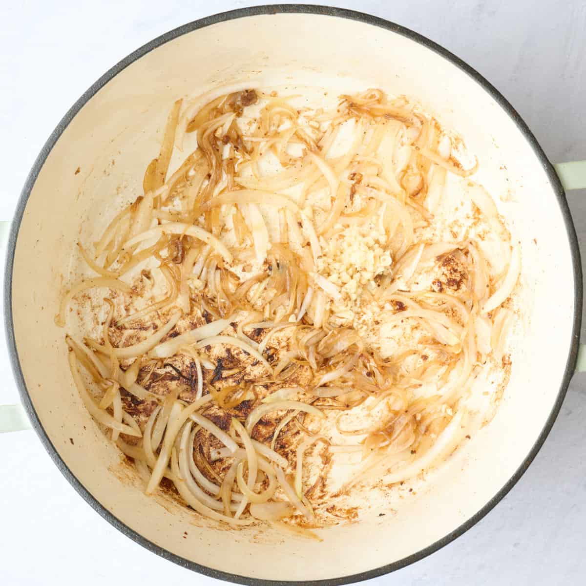 Beef removed with sliced onions added and cooked with garlic on top.