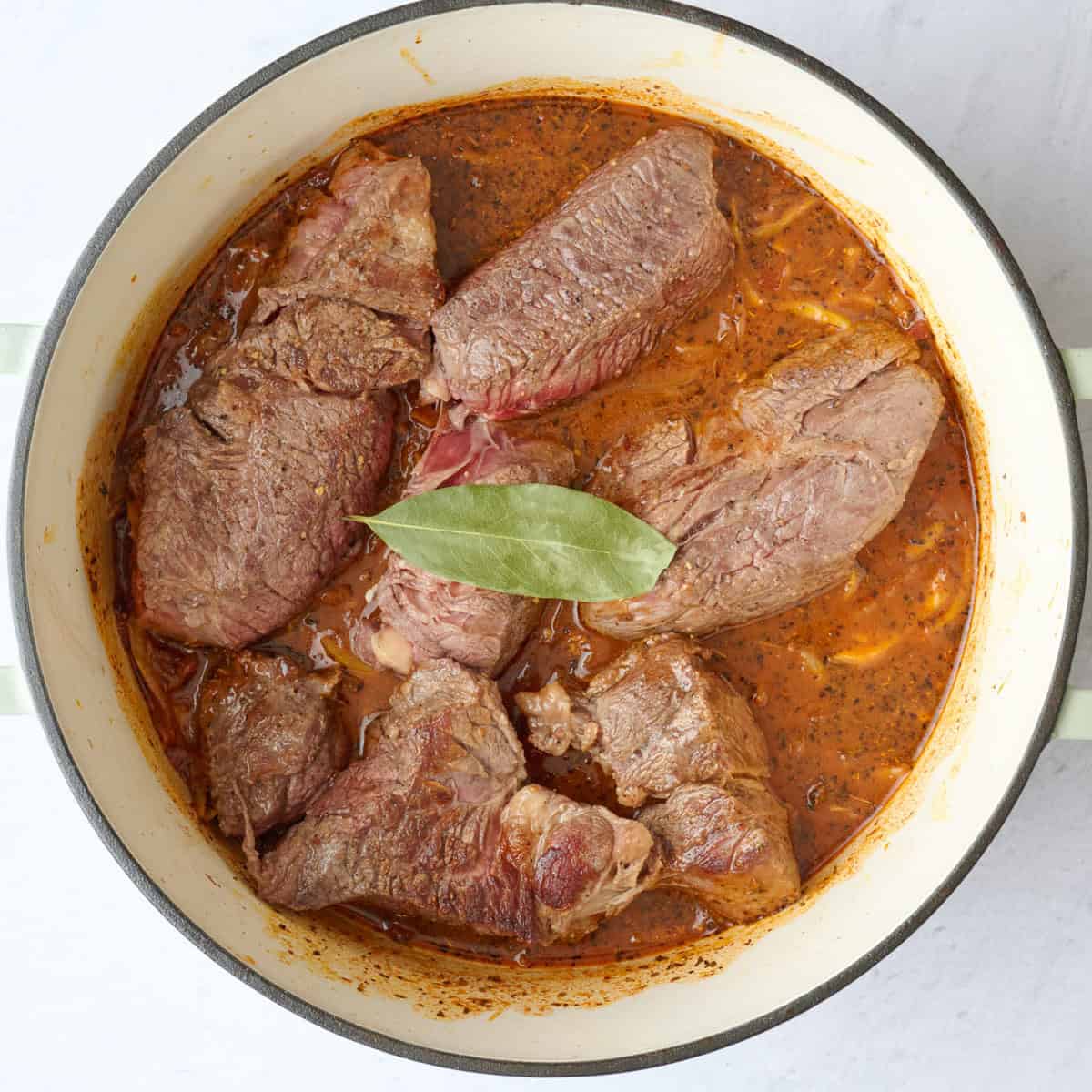 Broth, juices, beef and bay leaf added.