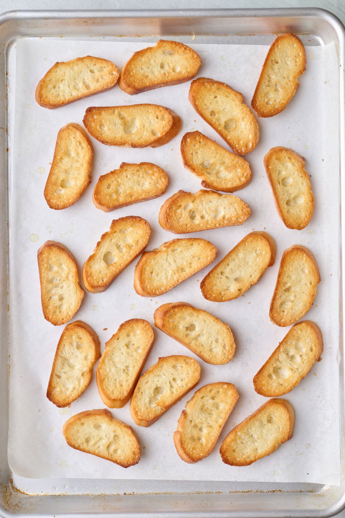 Toasted bread slices on a sheet pan.