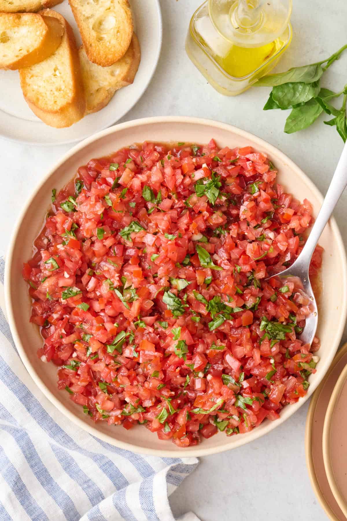Bowl of tomato bruschetta mixture with toasted crostini's nearby.