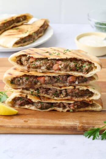 Arayes stacked up on a cutting board showing the ground beef filling.