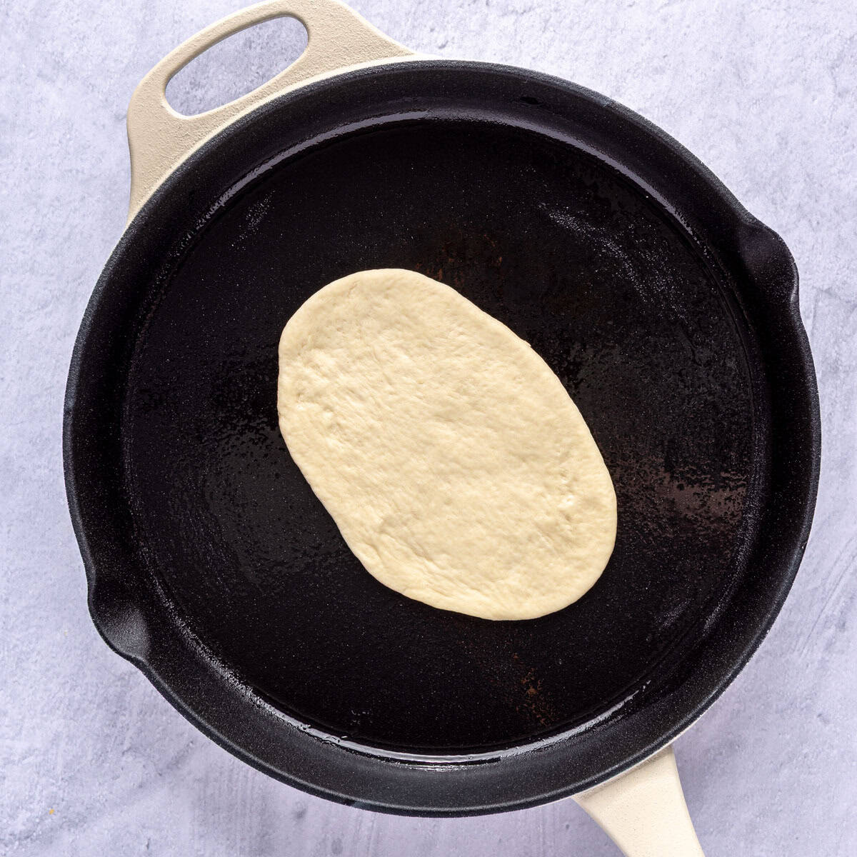 One naan dough in an oiled skillet.