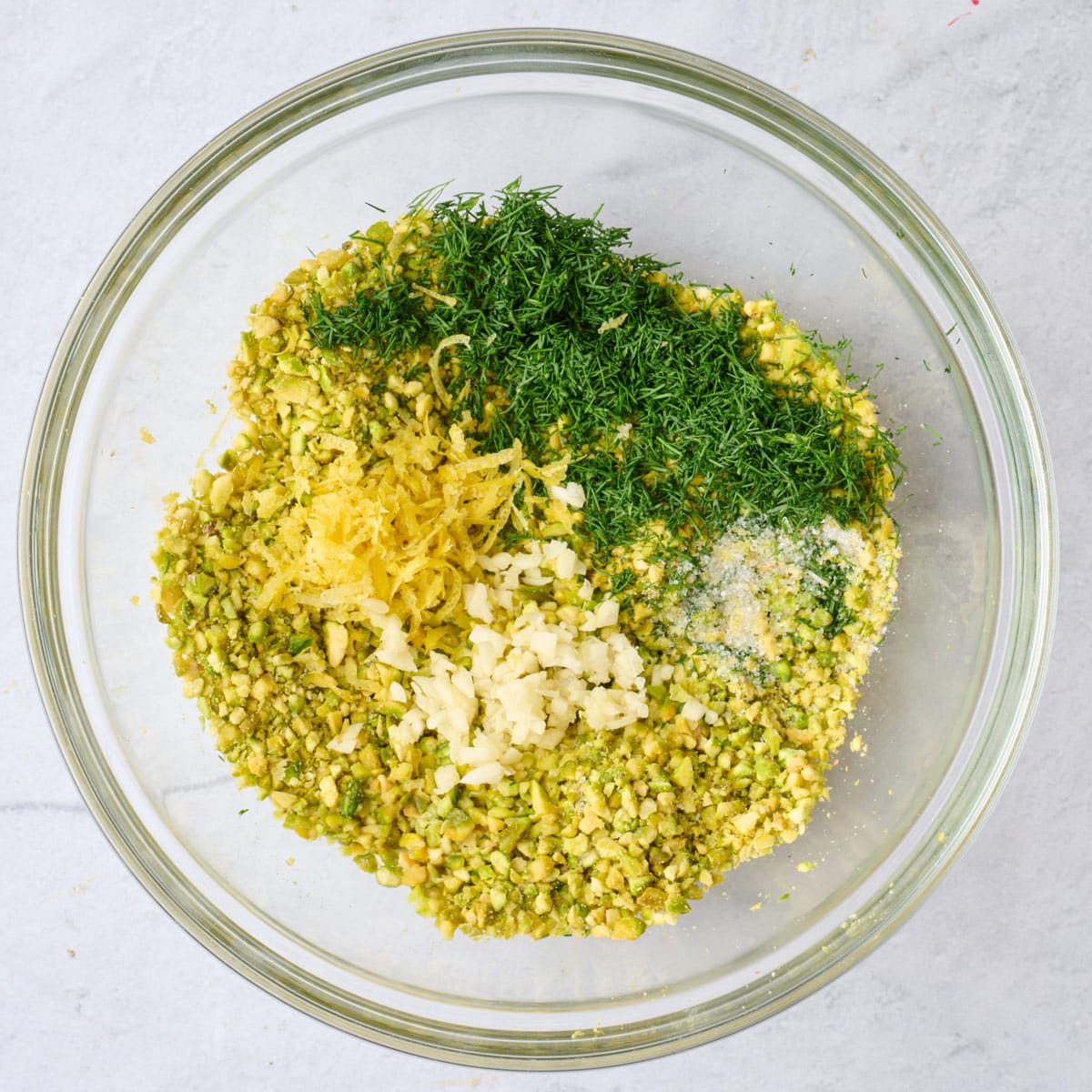 Chopped pistachios, oil, dill, lemon zest and juice, garlic and salt in a small bowl.