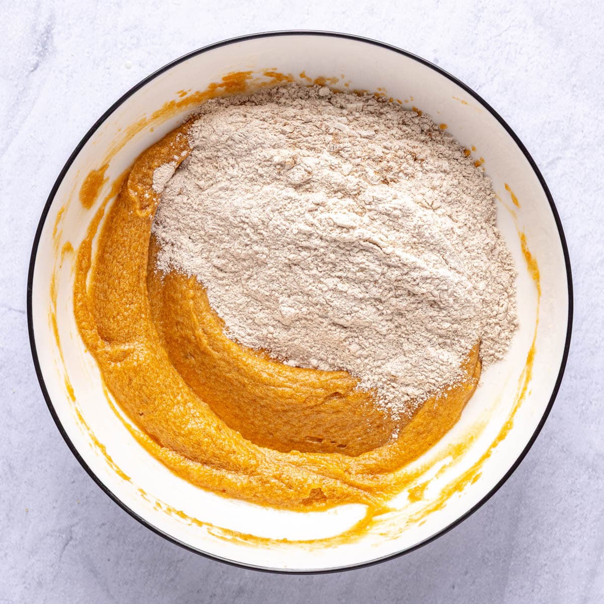 Pumpkin mixture in a bowl with dry ingredients added.