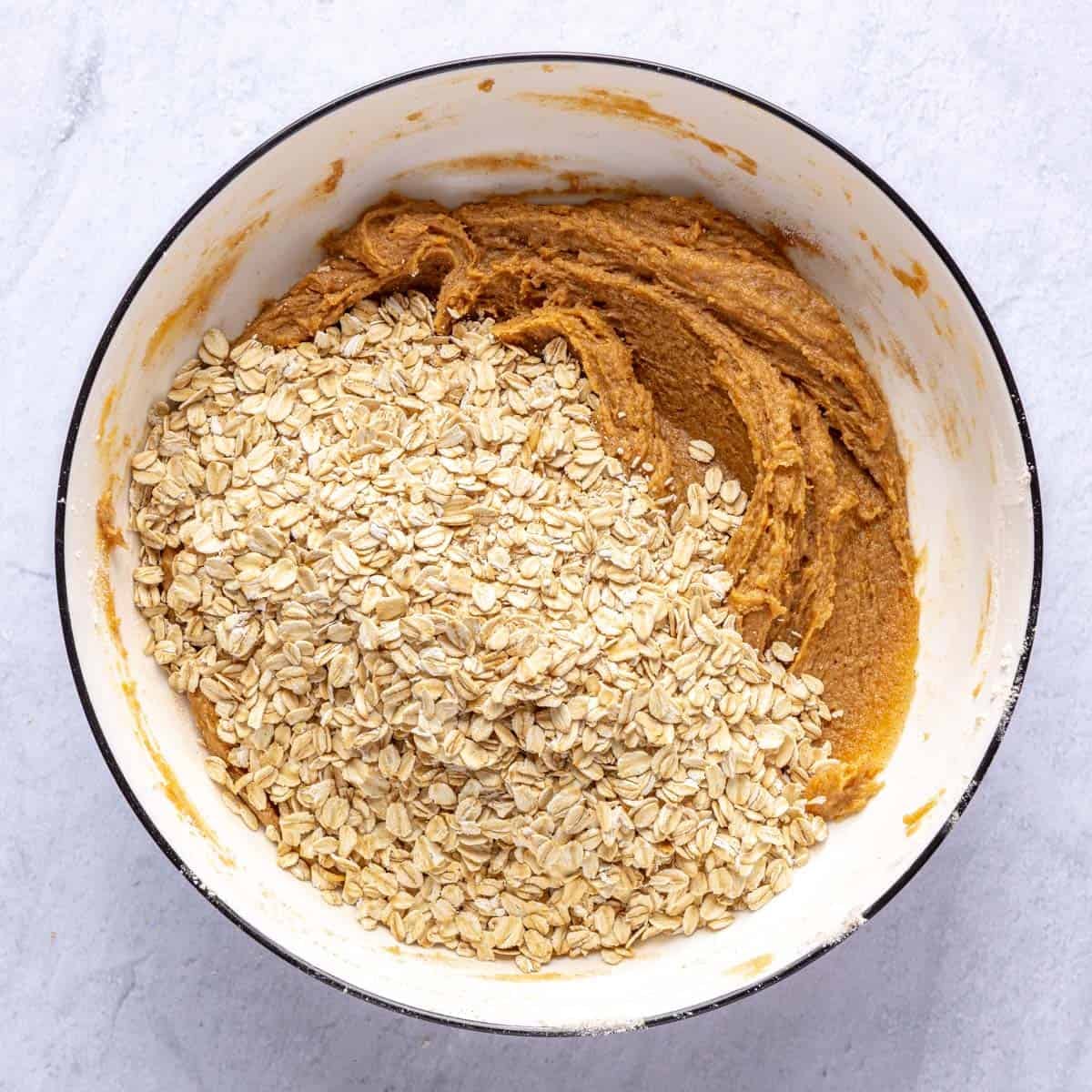 Cookie dough in a bowl with oats added.