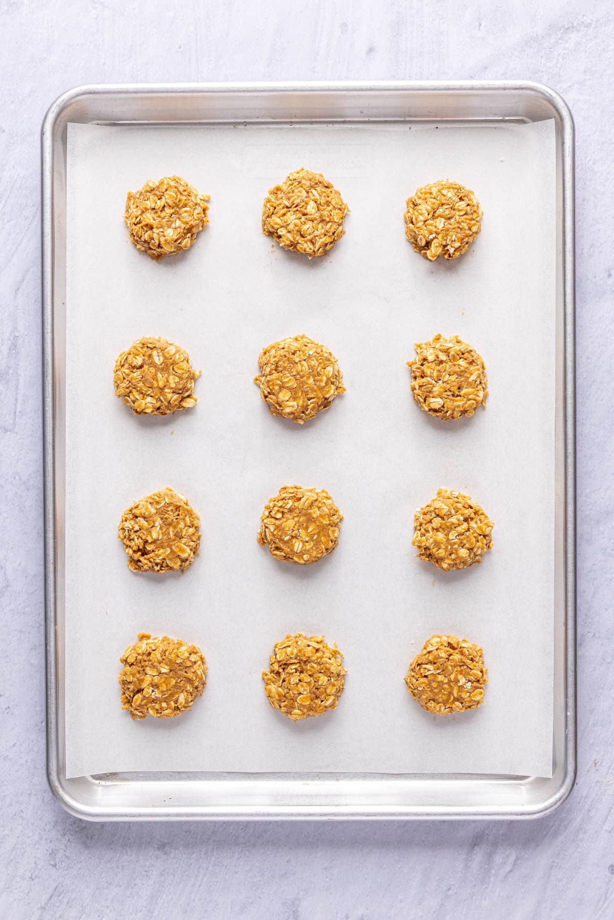Cookies scooped and flattened on a parchment lined baking sheet.