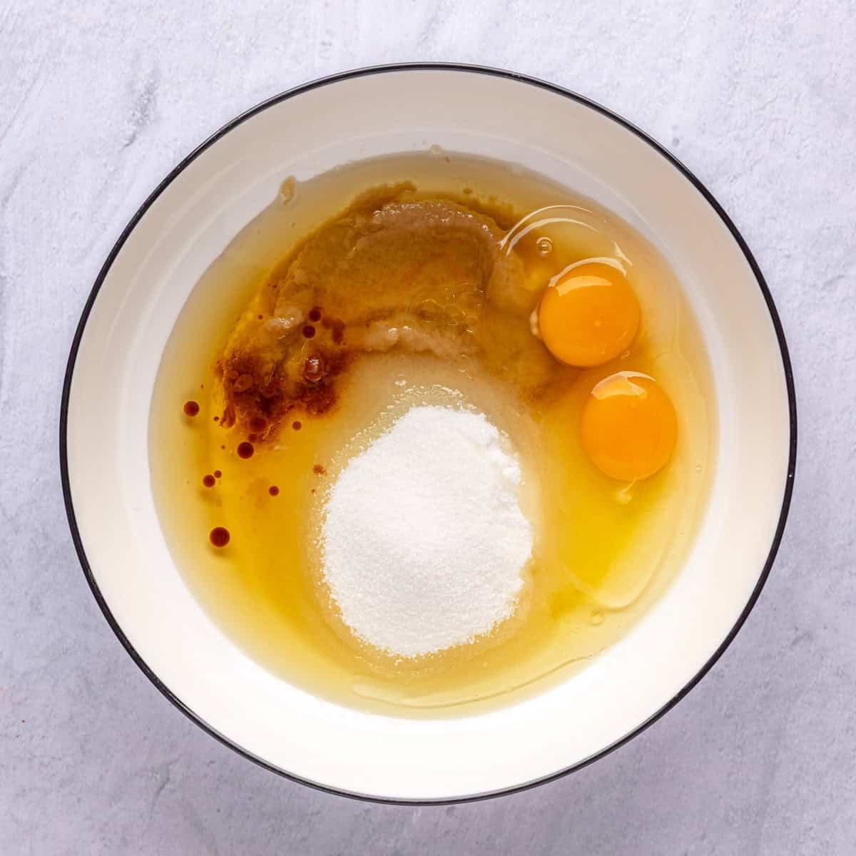 Eggs, sugar, oil, applesauce, and vanilla in a bowl before mixing.