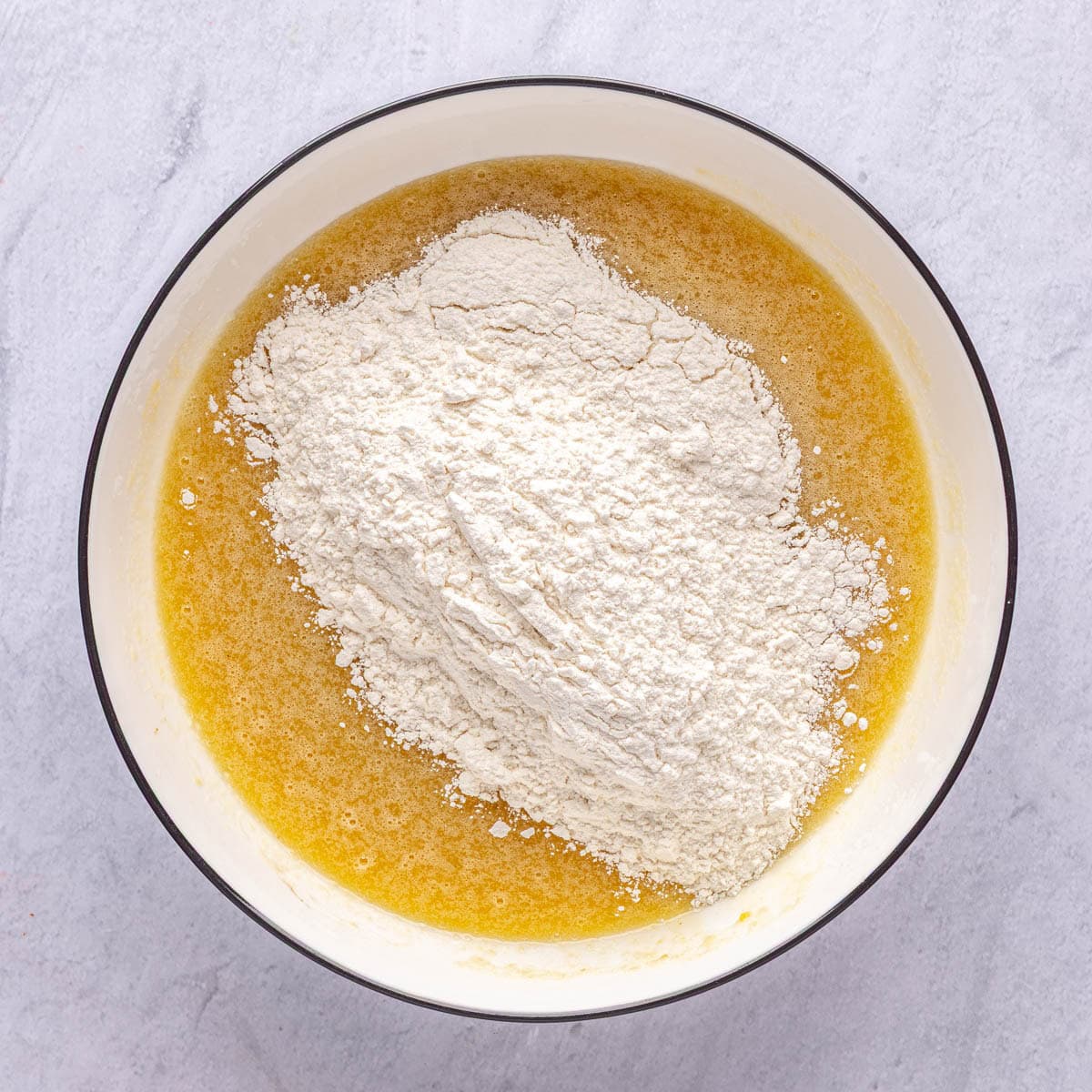Wet ingredients mixed in a bowl with flour mixture added on top.