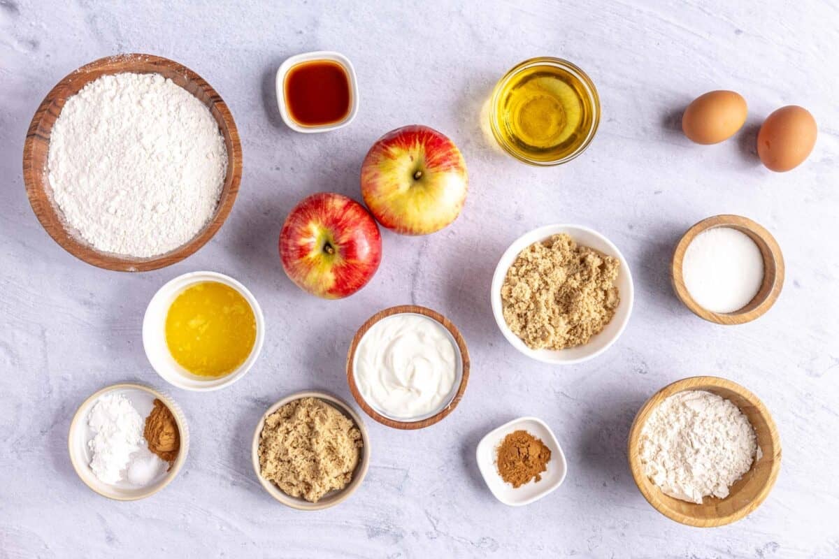 Ingredients for recipe: flour, vanilla, apples, melted butter, cinnamon, salt, baking powder, brown sugar, yogurt, sugar oil, and eggs.