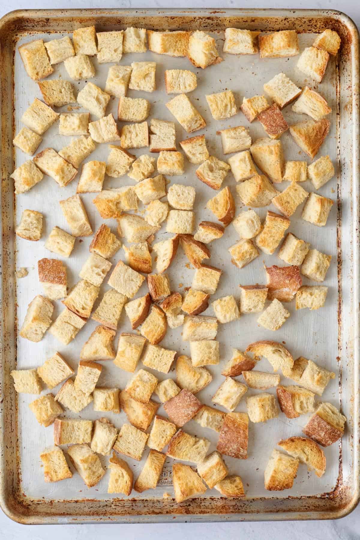 Cubed bread on a sheet pan after baked and toasted.
