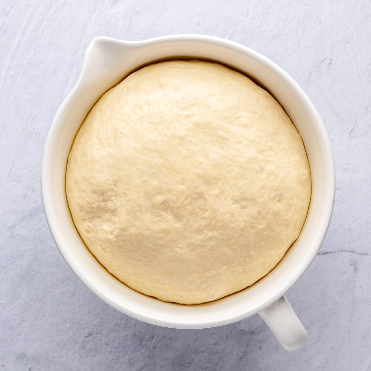 A risen dough in a large oiled bowl.
