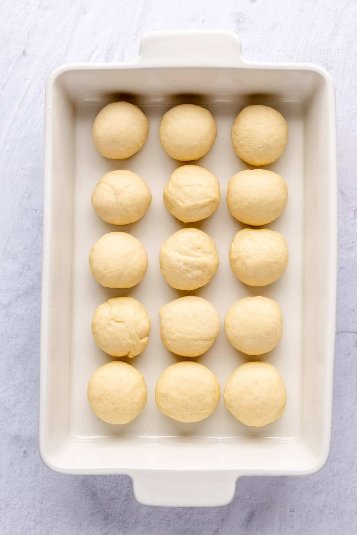 A baking dish with dough rolled into balls before rising.