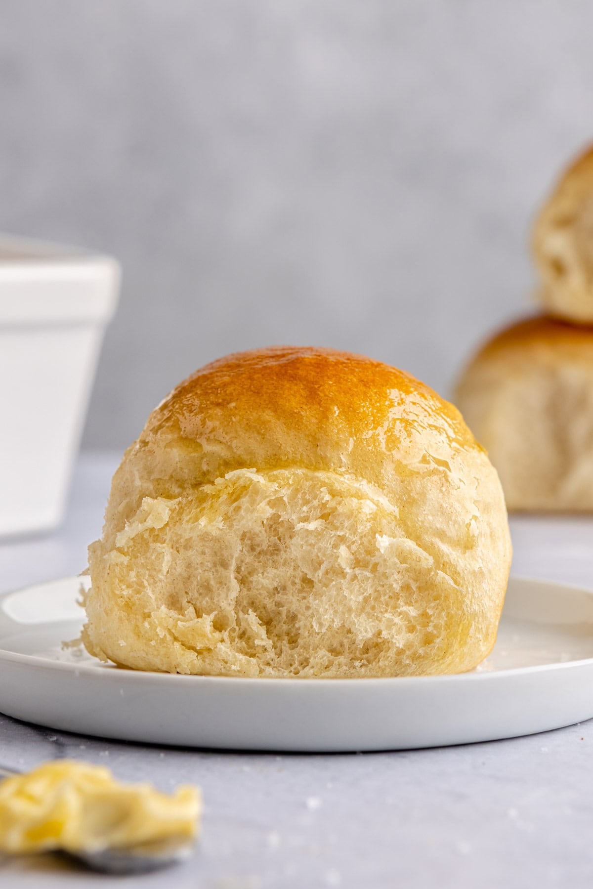 A soft homemade dinner roll on a plate brushed with oil.