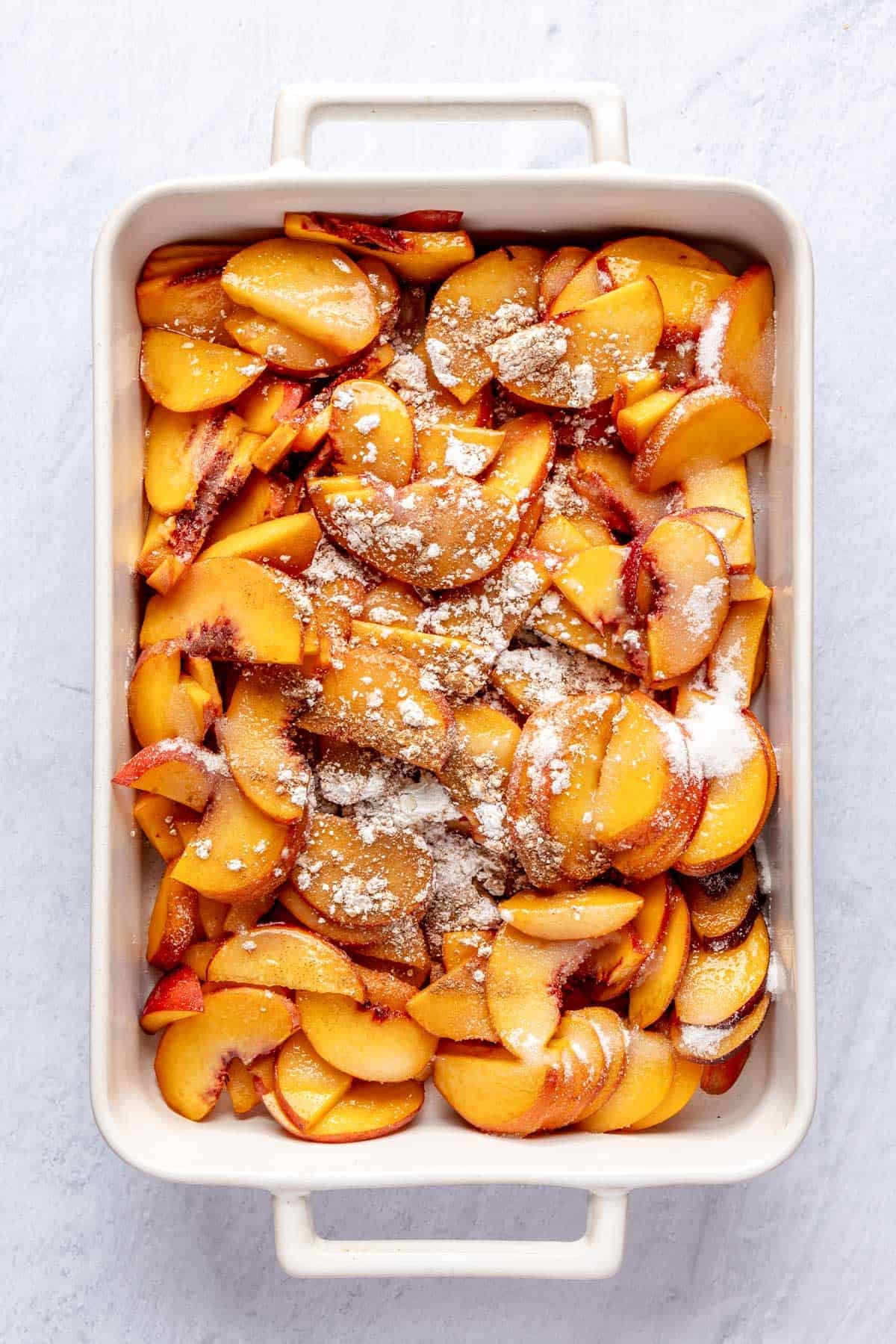 Sliced peaches with cornstarch and sugar mixes on top.