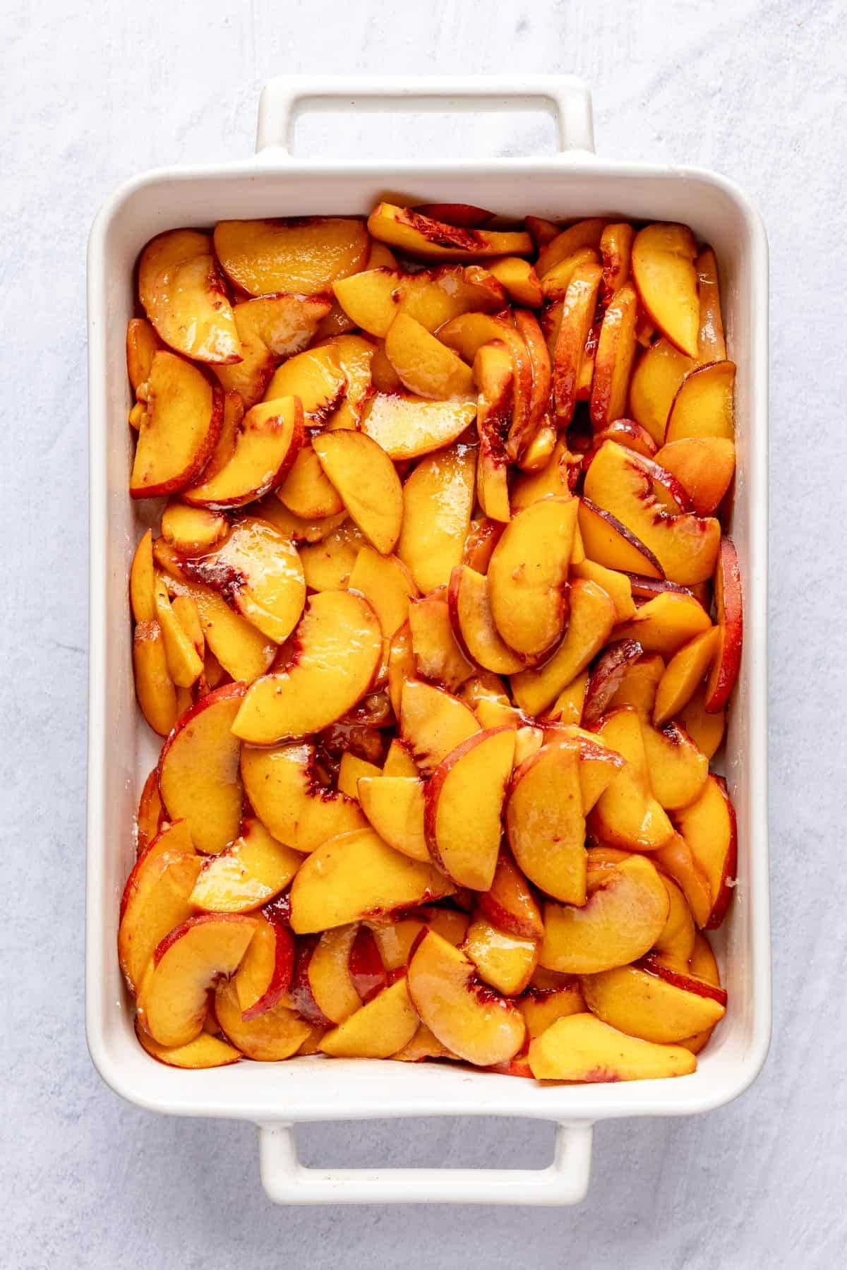 Sliced peaches in a baking dish.