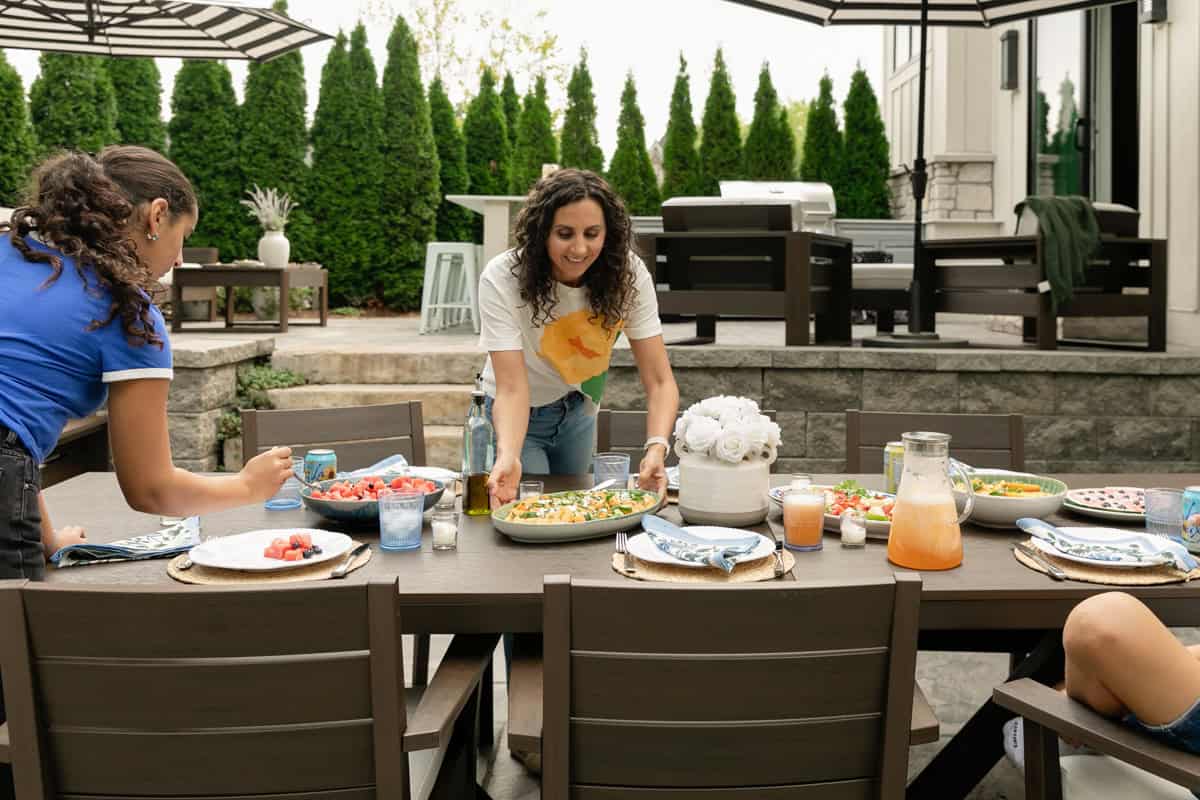 Yumna and daughter in outdoor patio serving food on polywood furniture