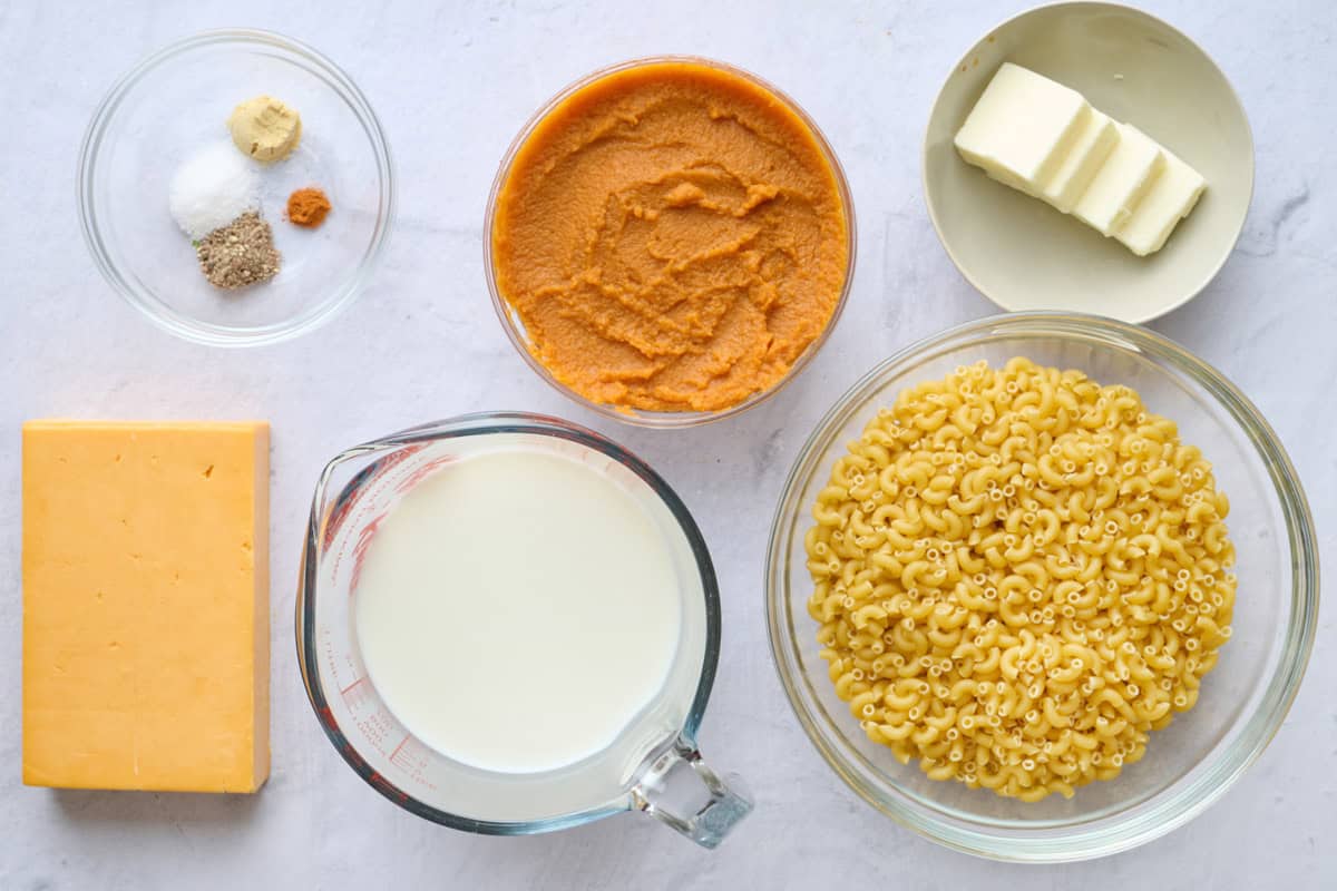 Ingredients for recipe: seasonings, pumpkin puree, cheese, milk, butter and dried macaroni pasta.