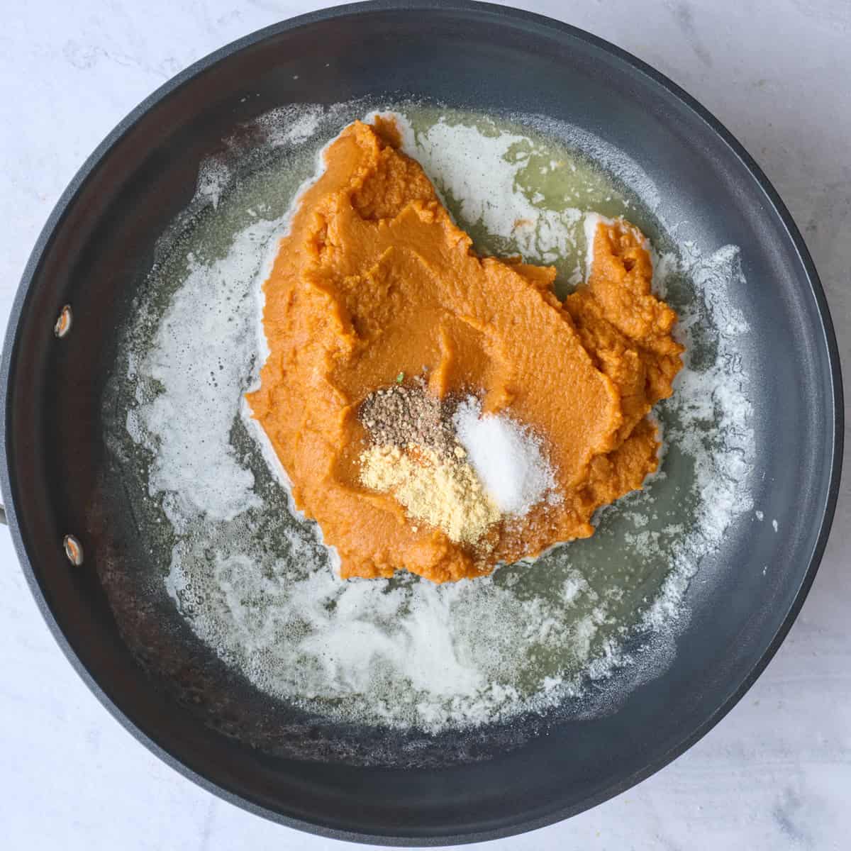 Melted butter in a skillet with pumpkin puree and seasonings added.