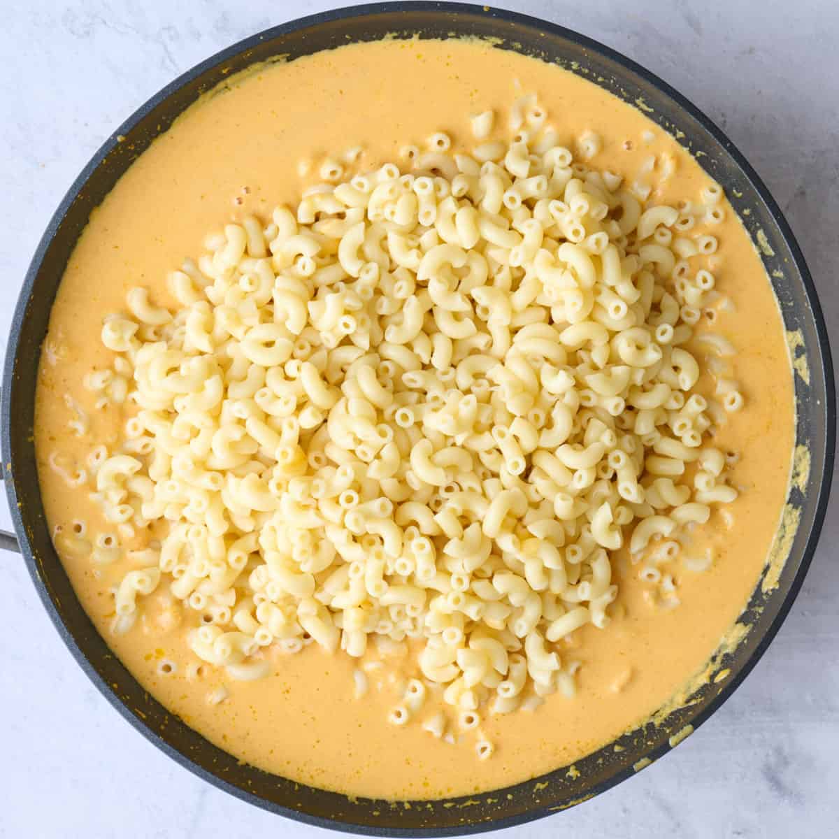 Cooked pasta added to creamy pumpkin sauce.