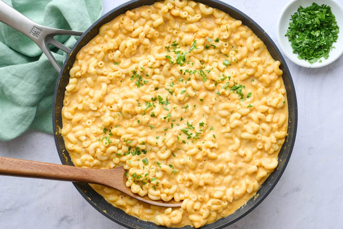 Pumpkin mac & cheese in skillet garnished with chopped parsley.