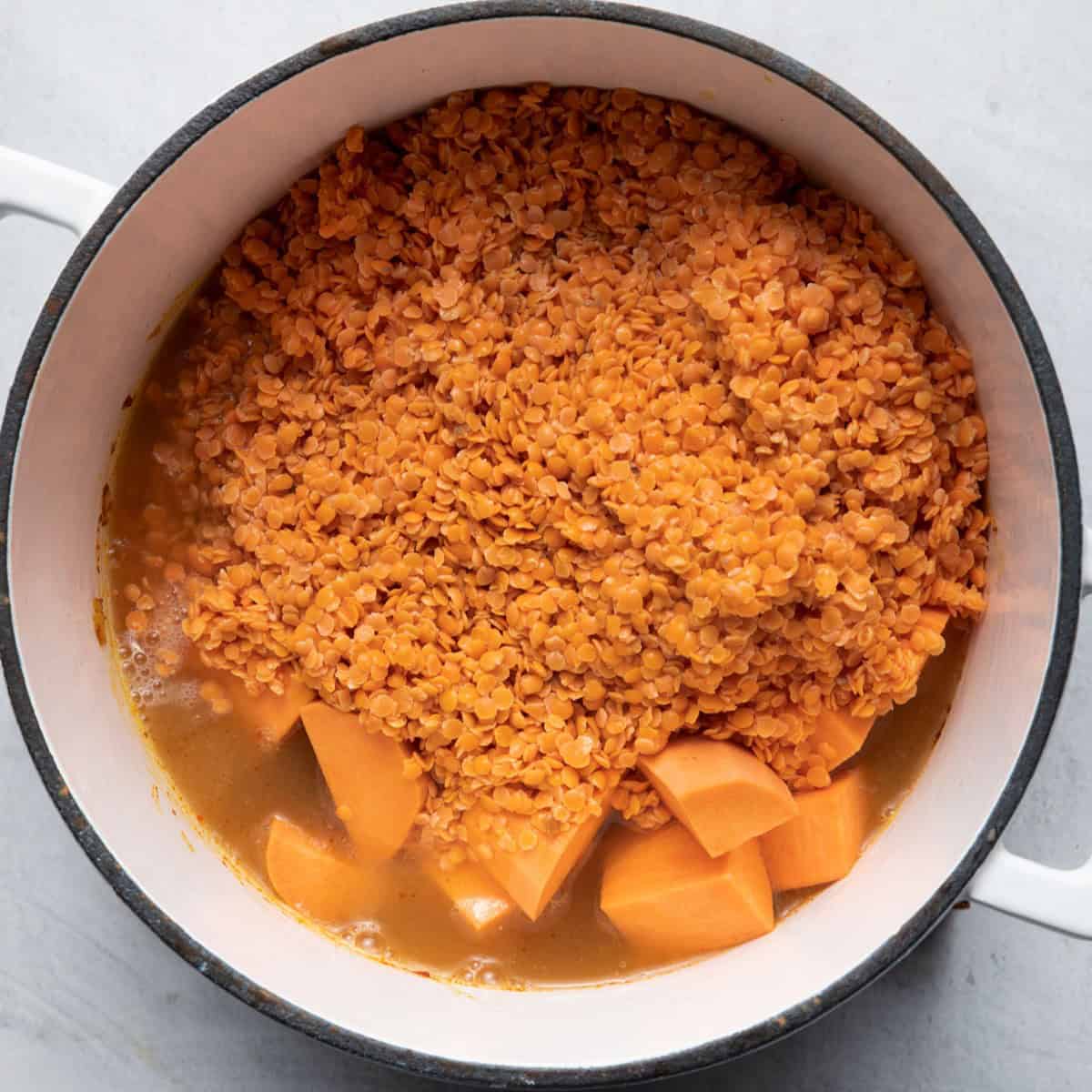 Red lentils and sweet potatoes added with broth to pot.