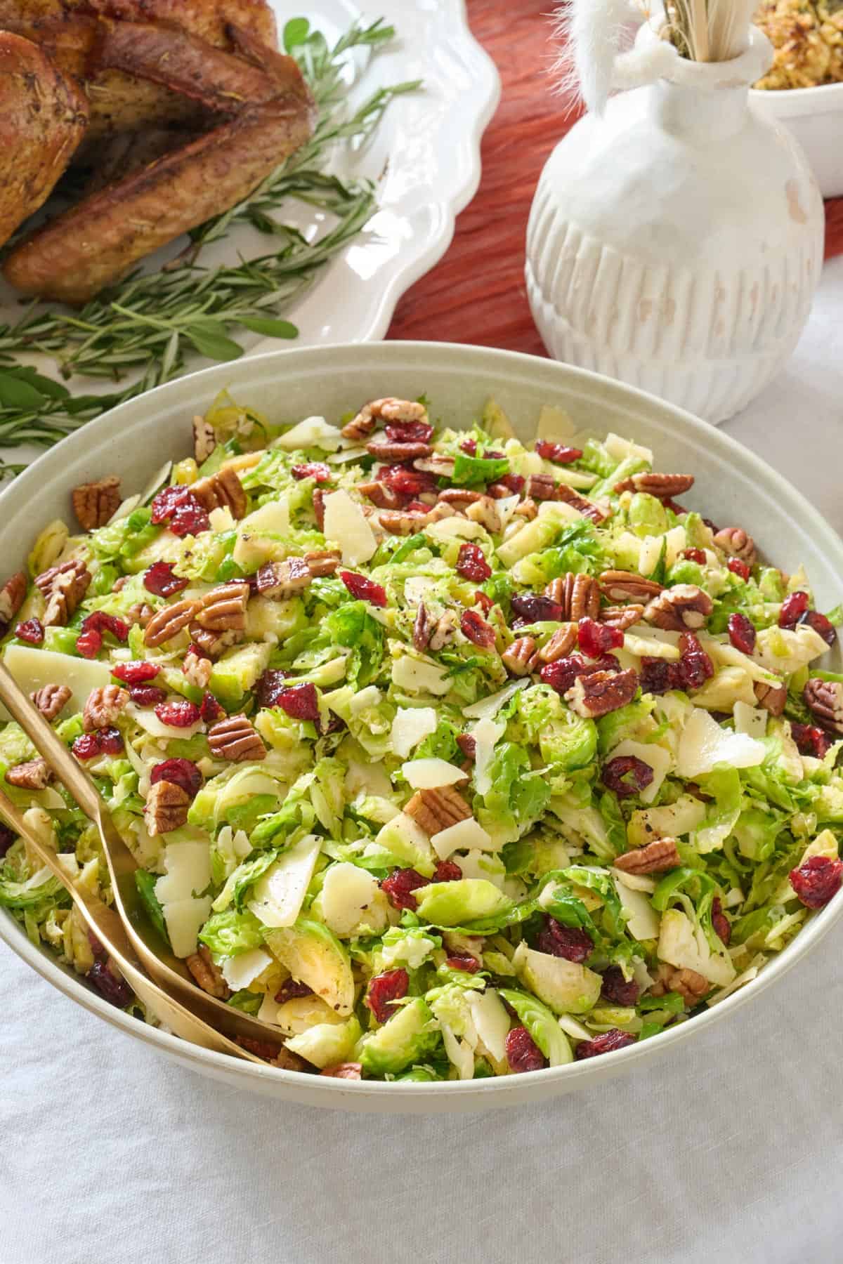 Holiday shaved brussel sprouts salad in a serving bowl with dried cranberries and pecans.