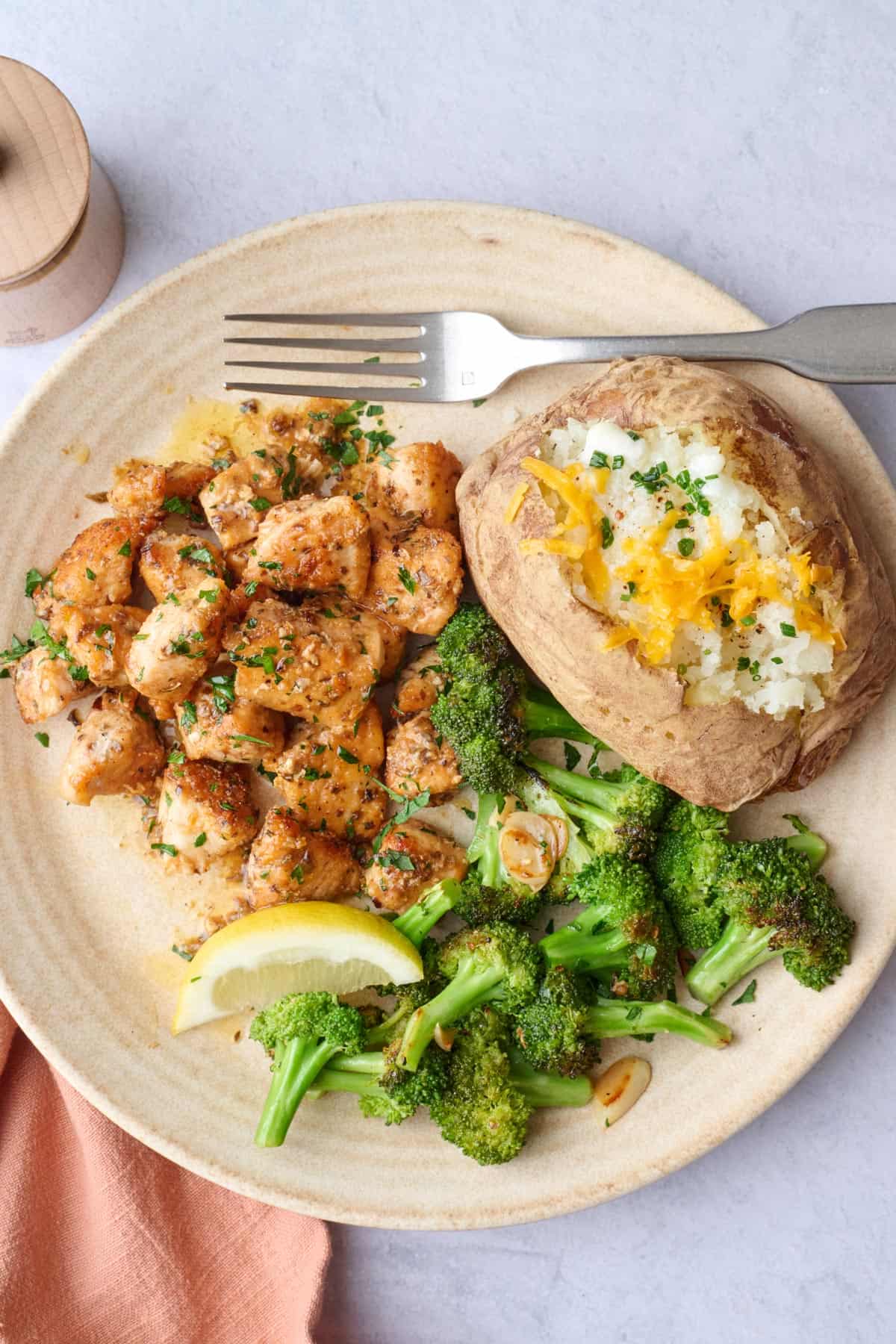 Chicken breast bites recipe on a plate served with a baked potato and broccoli.