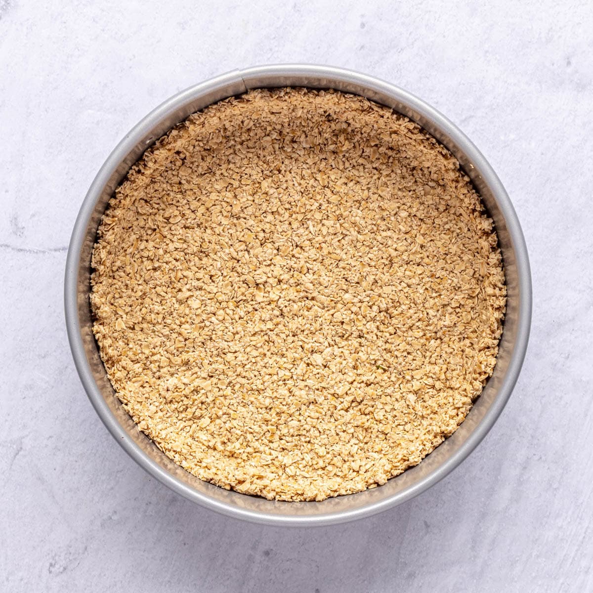 Baked oat crust in a springform pan for cottage cheesecake recipe.