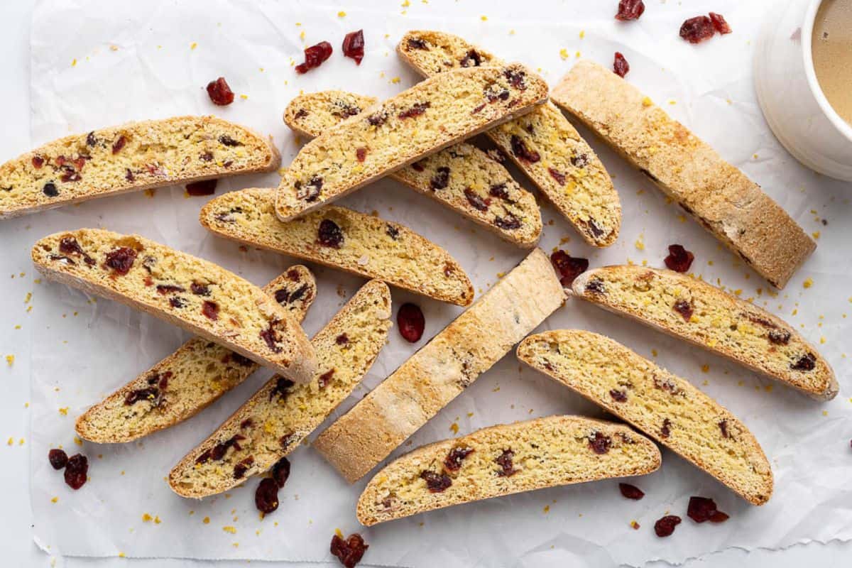 Easy cranberry orange biscotti recipe on parchment paper with extra dried cranberries and orange zest sprinkled on top.