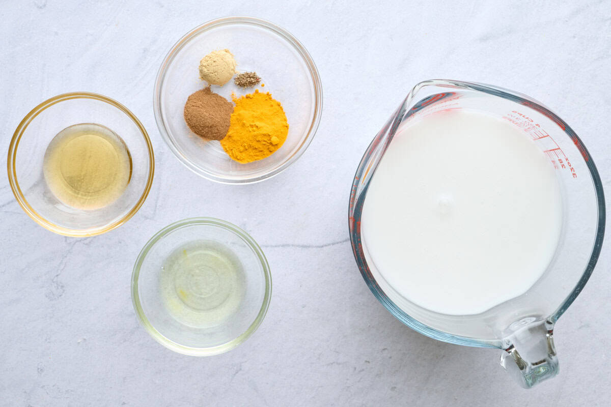 Ingredients for latte recipe: coconut oil, honey, ground turmeric, cinnamon ginger and black pepper, and milk.