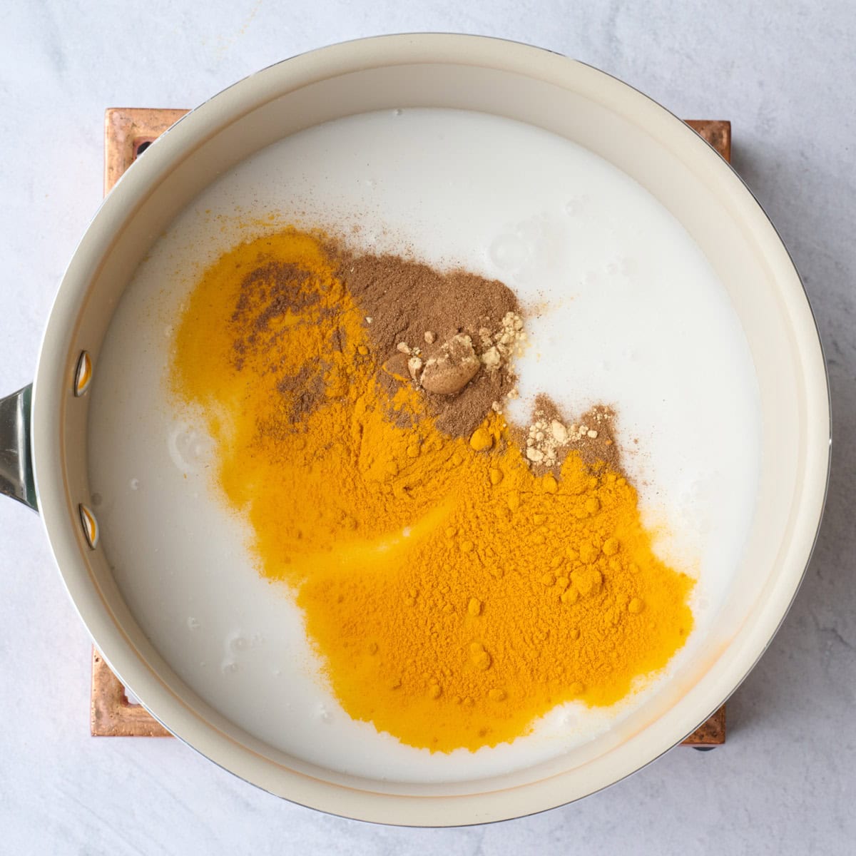 A small saucepan with milk and warm spices for latte recipe before mixing together.