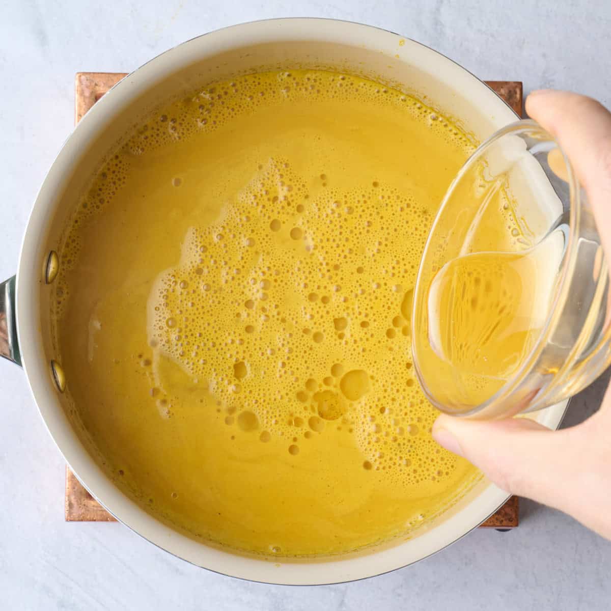 Golden milk latte in a pot with coconut oil before poured in.